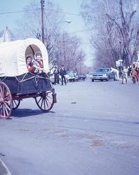Women Look Out of Back of Covered Wagon at Maple Festival Parade