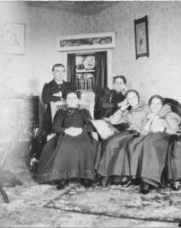 A man and four women posing in J.M. Olinger's parlor