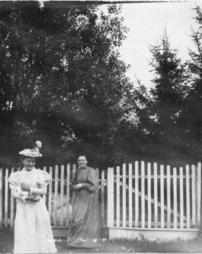 Ladies standing by fence collecting something in their arms