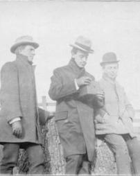 Three men on stump with a camera