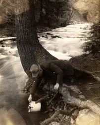 Unidentified man getting water from stream