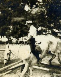 Photograph of Portus Acheson riding a horse, jumping