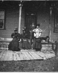 Men peeking out the window at four people on a porch