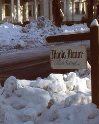 Maple Manor Sign Along Road in Snow