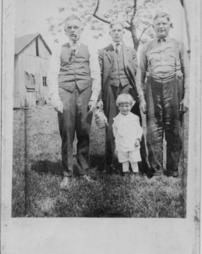 Toddler standing outside with three men
