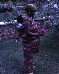 Woman picking flowers with child on her back