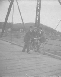 Two men helping a child ride a bicycle on Broadway Bridge