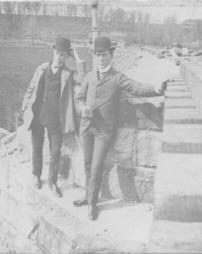 Two men on side of railroad bridge
