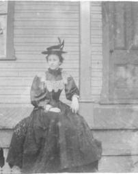 Woman in dark dress sitting on a porch