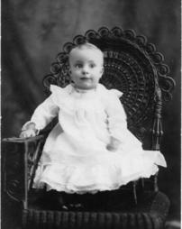 Bright-eyed baby in wicker chair