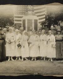 Group of nurses & citizens surrounding a monument