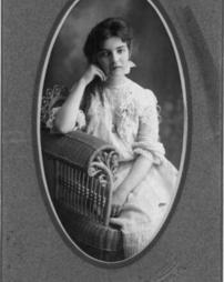 Grace Kendall posing in a wicker chair