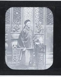 China. [Man wearing Traditional Clothing in Room with Potted Plants]