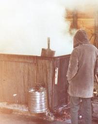 Man in Coat at Steaming Evaporator in Sugar Camp