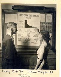 Two students look at front hall bulletin board, 1938