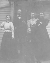 Four women and one man stand under a porch