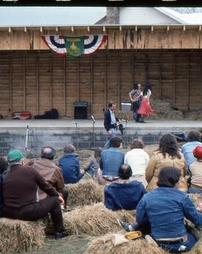 Audience on Straw Bales Watch Two Cloggers and Musicians on Festival Park  Stage
