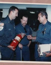 Three firefighters inspecting fire extinguisher